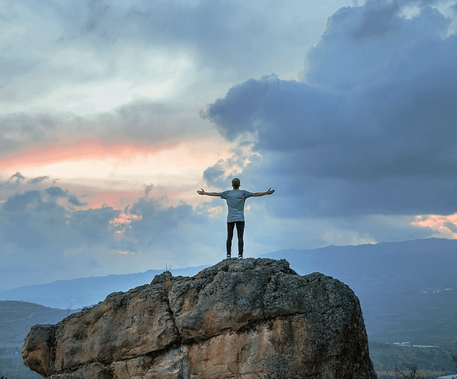 Person standing on a rock with arms wide open